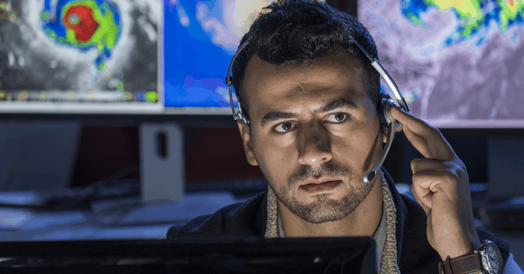 man in a command center with a headset and a computer