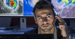 man in a command center with a headset and a computer