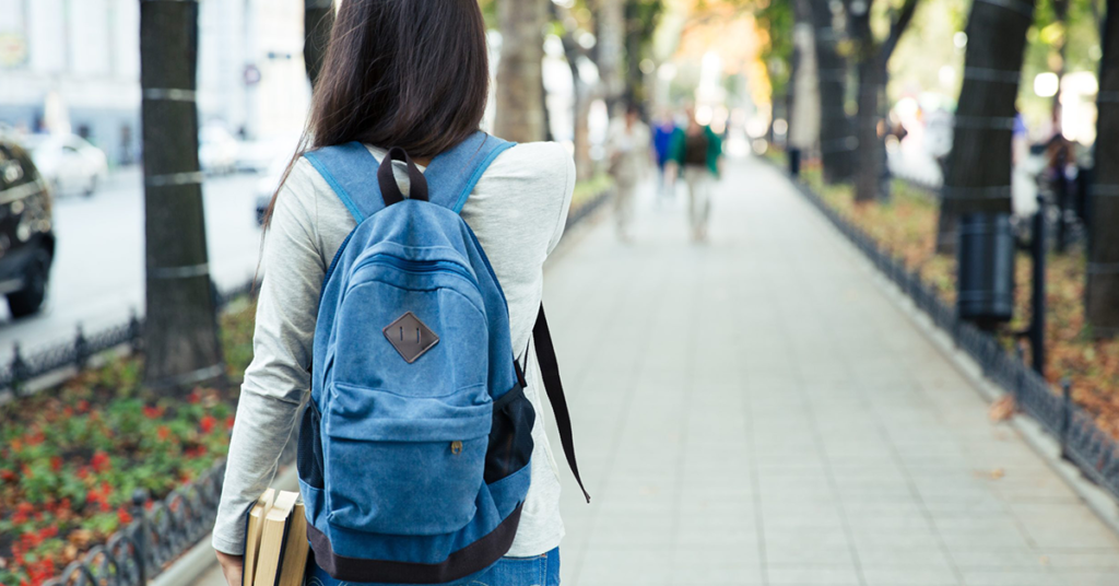 student wearing backpack walking through campus