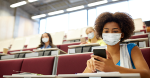 masked student sitting in a college classroom