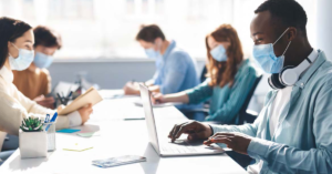 students sitting at a table in college or university all wearing masks