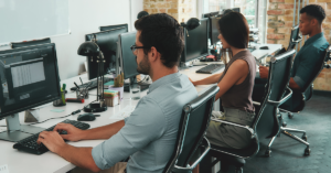 employees sitting at desk working on computers