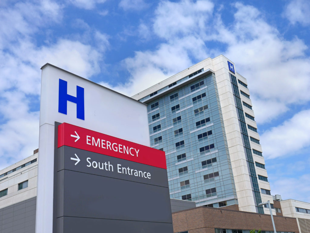 hospital sign with directions to emergency room with hospital in background