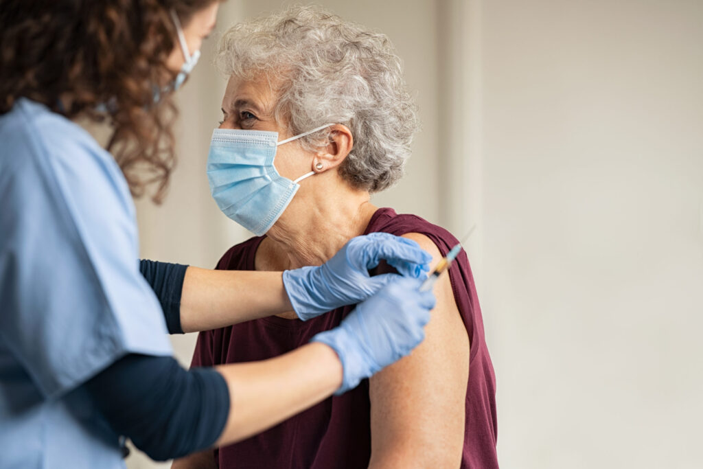 doctor giving covid vaccine to elderly woman in a mask