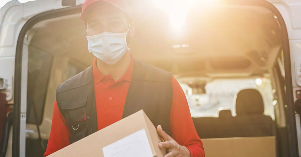 man wearing mask delivering resources from a van