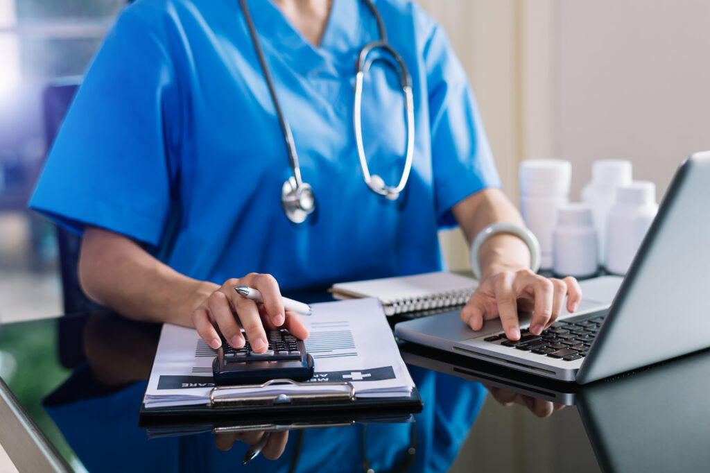 Healthcare costs and fees concept.Hand of smart doctor used a calculator and smartphone, tablet for medical costs at hospital.