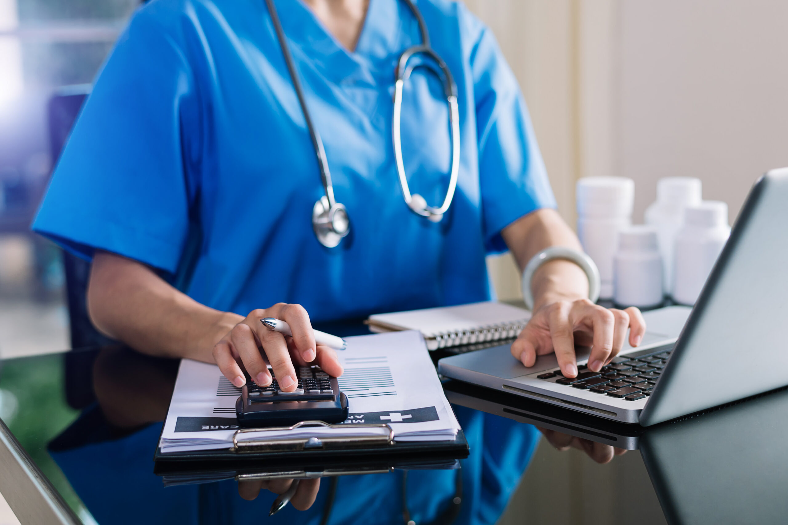 Healthcare costs and fees concept.Hand of smart doctor used a calculator and smartphone, tablet for medical costs at hospital.